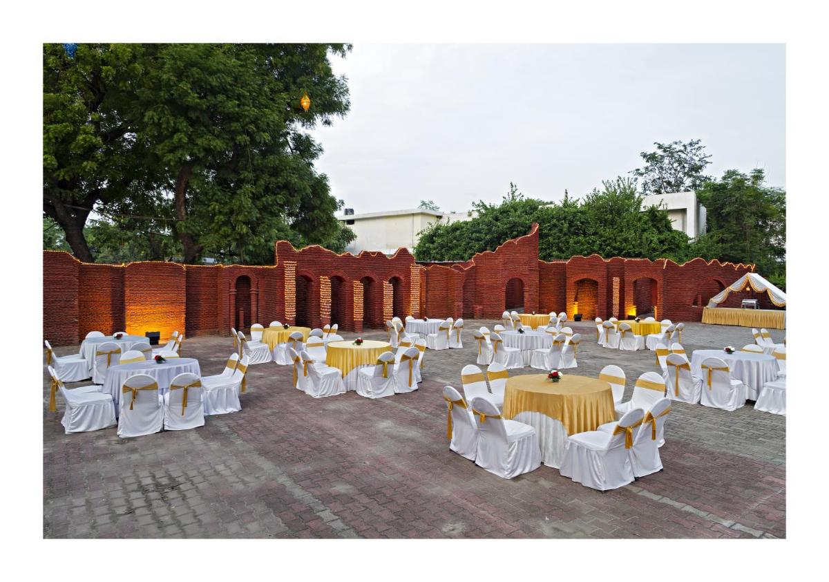 a group of tables and chairs in front of a brick wall at Clarks Avadh in Lucknow