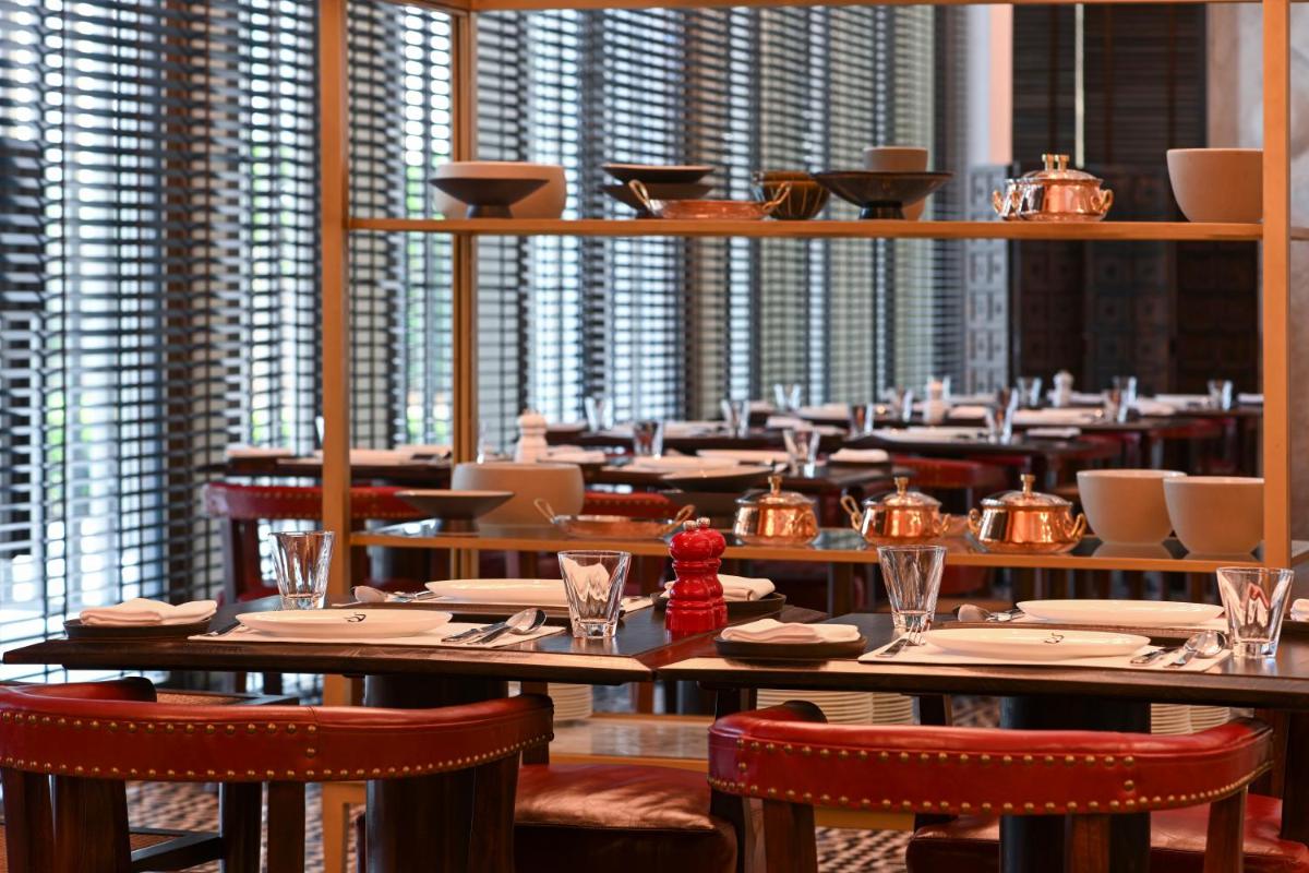 a dining room with tables and chairs and windows at Grand Hyatt Gurgaon in Gurgaon