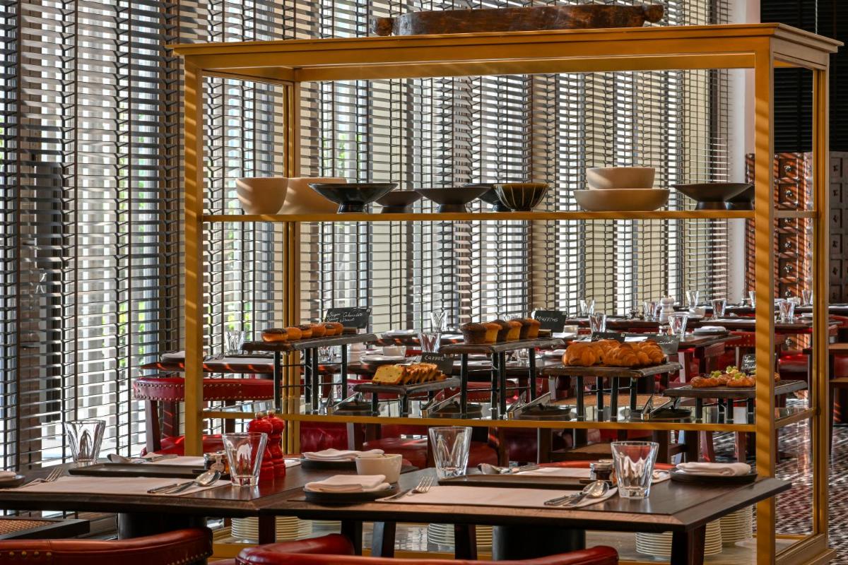a dining room with tables and chairs and windows at Grand Hyatt Gurgaon in Gurgaon