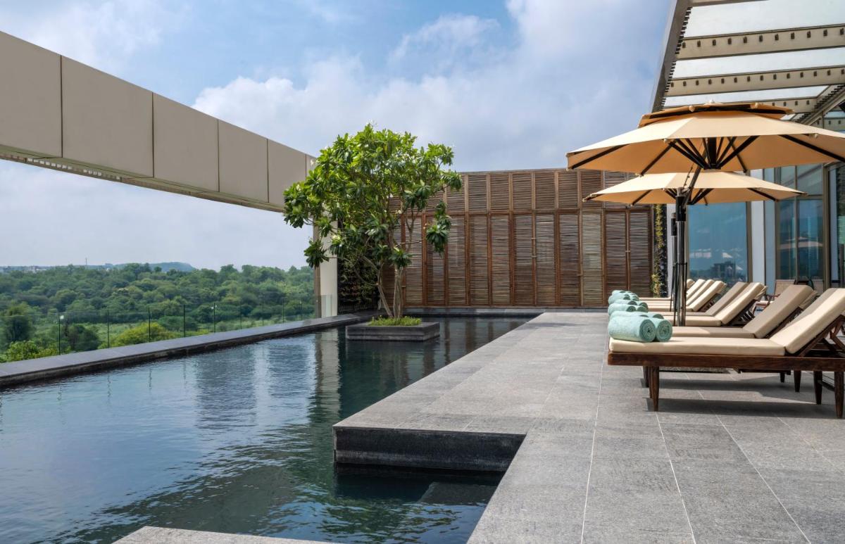 a pool with chairs and umbrellas on a building at Grand Hyatt Gurgaon in Gurgaon