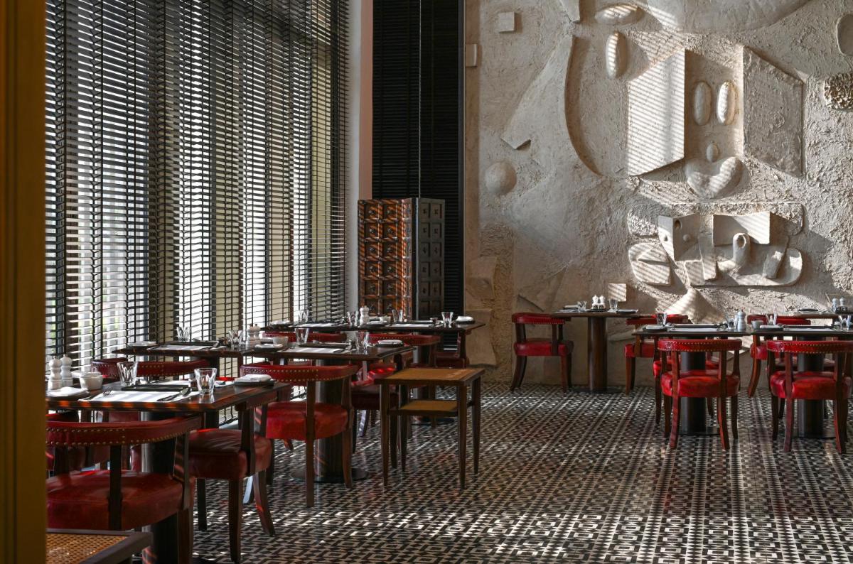 a dining room with tables and red chairs at Grand Hyatt Gurgaon in Gurgaon