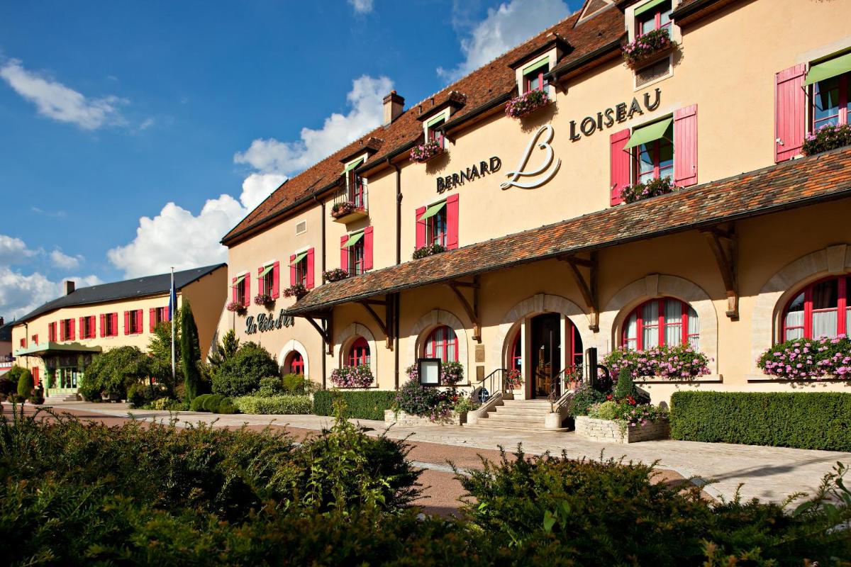 un grand bâtiment avec des fenêtres rouges et des plantes devant dans l'établissement Relais Bernard Loiseau, à Saulieu