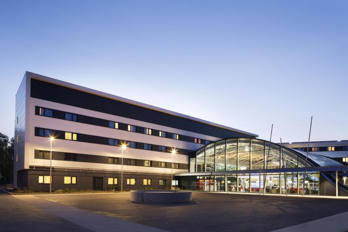 un grand bâtiment de bureau avec une grande façade en verre dans l'établissement Oceania Paris Roissy CDG, au Mesnil-Amelot