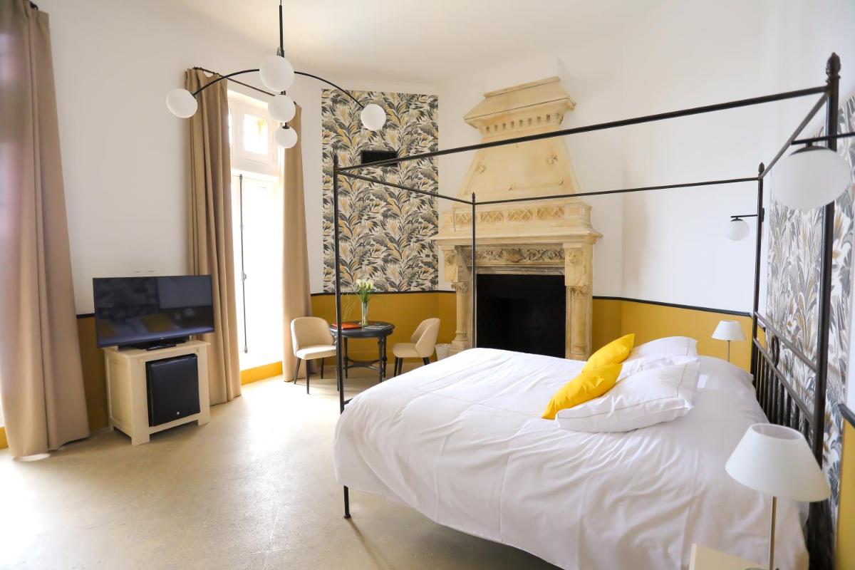 - une chambre avec un lit blanc et une cheminée dans l'établissement Hostellerie du Château des Fines Roches, à Châteauneuf-du-Pape