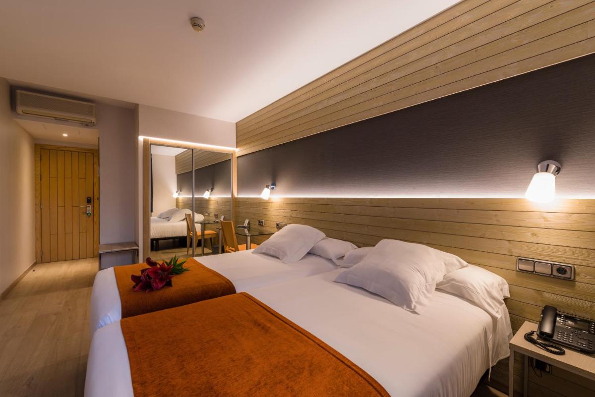 Una habitación de hotel con dos camas y un espejo. en Hotel Avenida, en A Coruña