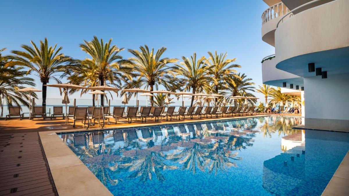 una piscina con sillas y palmeras en Hapimag Apartments Marbella, en Marbella