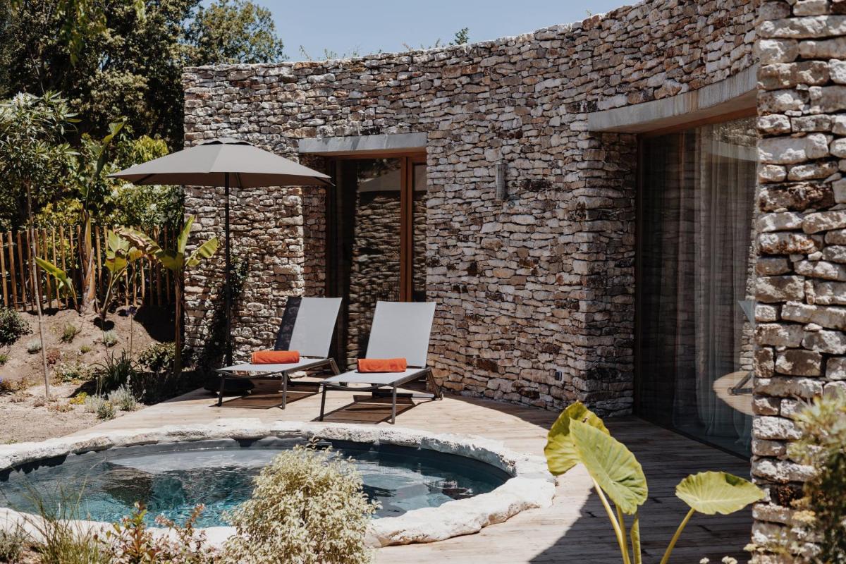 une terrasse avec un bain à remous, 2 chaises et un parasol dans l'établissement A SPERANZA Suites avec piscine privative chauffée, à Bonifacio
