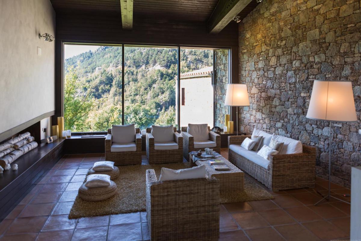Una sala de estar con sofás y una pared de piedra. en Hotel Rural-Spa Resguard Dels Vents, en Ribes de Freser