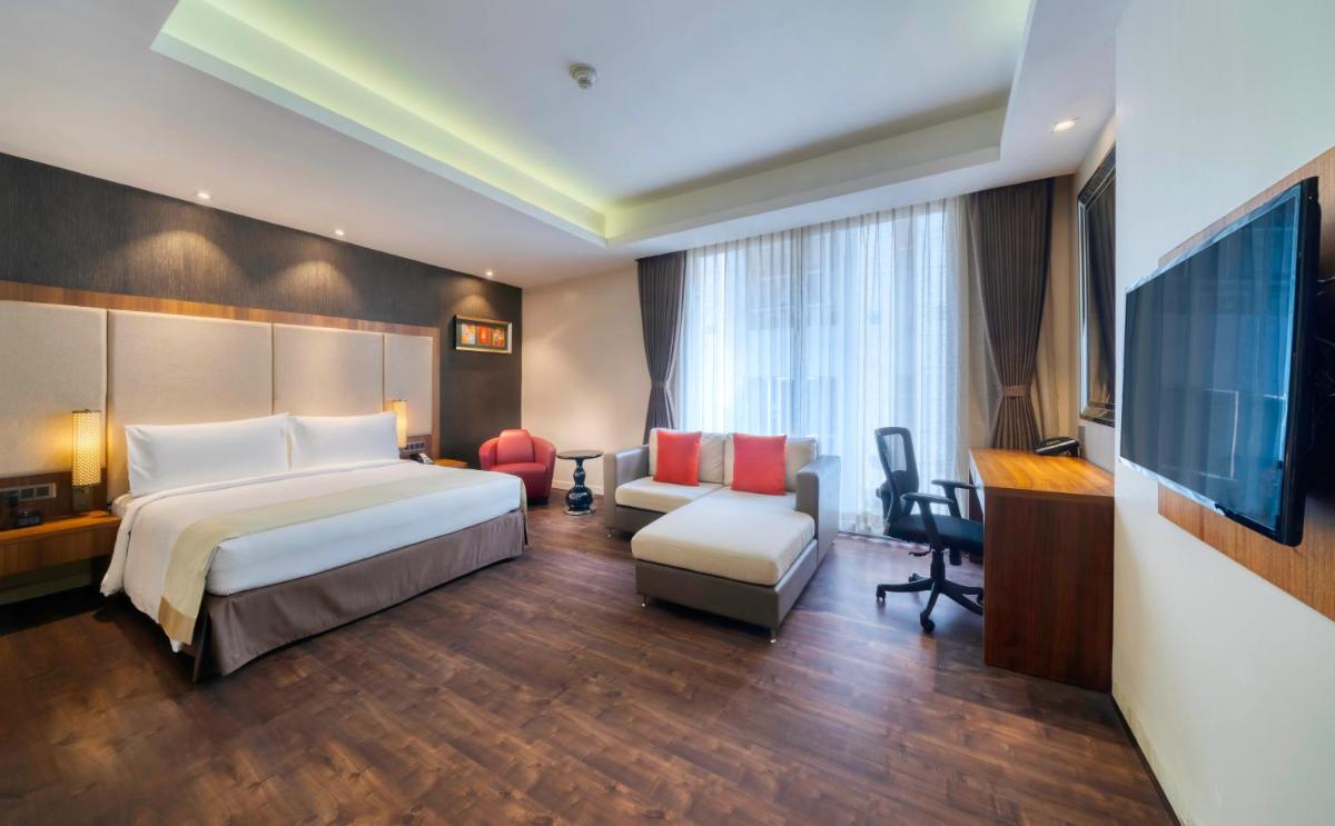 a bedroom with a bed and a desk and a television at Holiday Inn Kolkata Airport by IHG in Kolkata