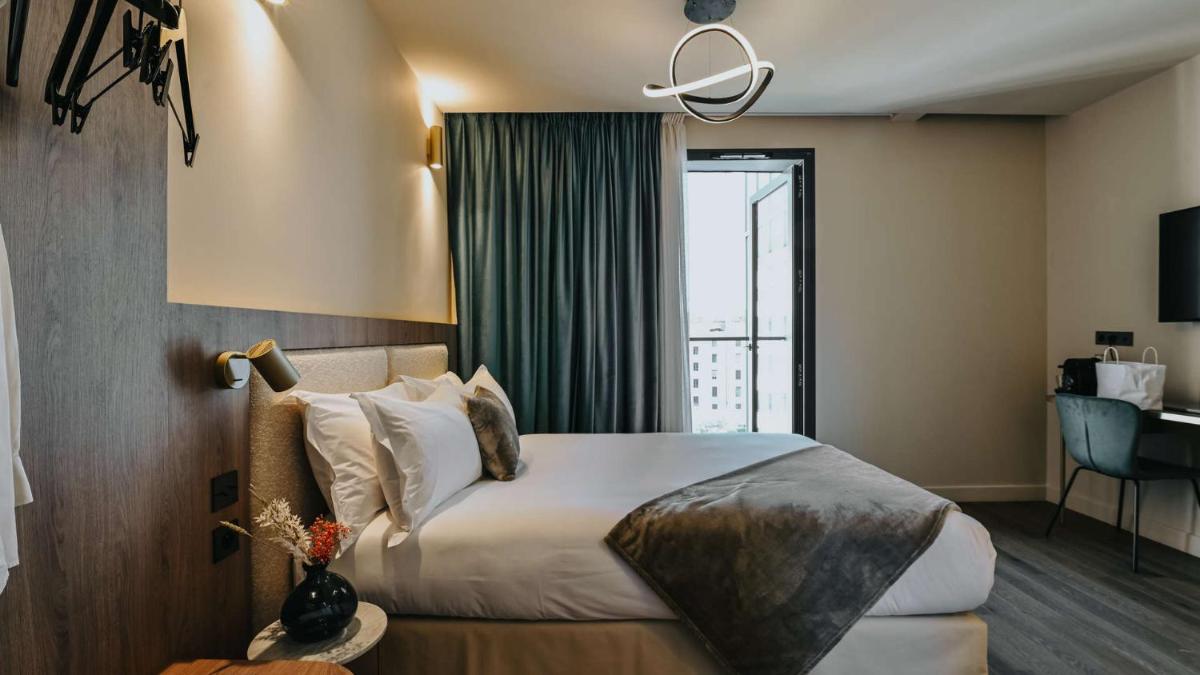 une chambre d'hôtel avec un lit et une grande fenêtre dans l'établissement Keystone Hôtel & Spa, à Lyon