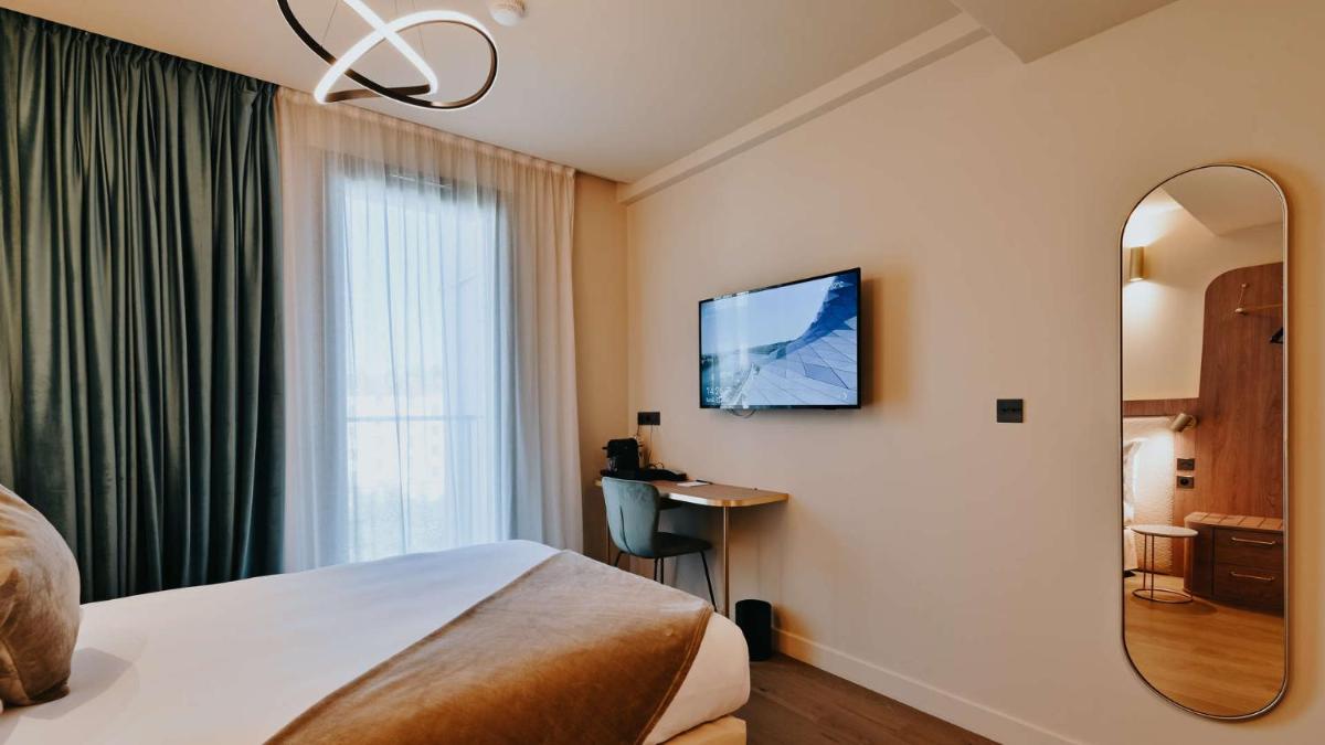 une chambre d'hôtel avec un lit et un miroir dans l'établissement Keystone Hôtel & Spa, à Lyon