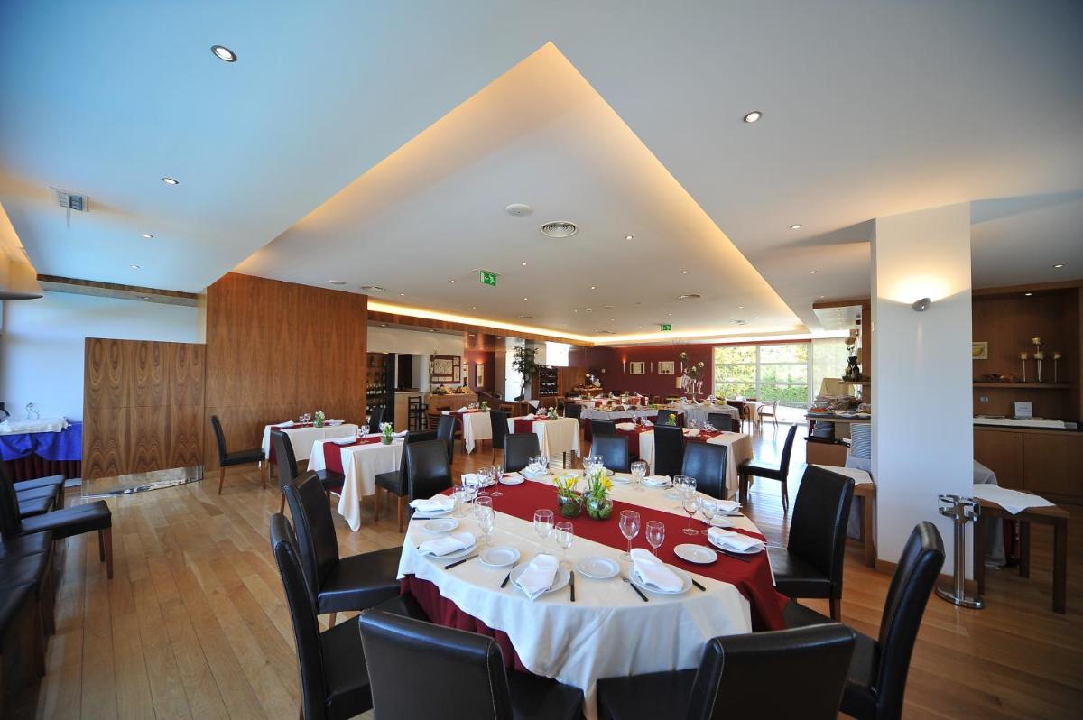 uma sala de jantar com mesas e cadeiras em um restaurante em Hotel Lusitania Congress & Spa na Guarda