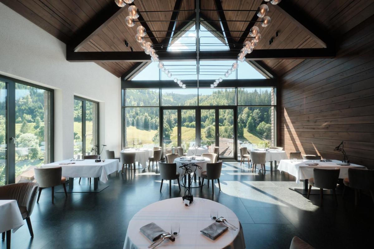 ein Restaurant mit weißen Tischen und Stühlen und großen Fenstern in der Unterkunft Hotel Traube Tonbach in Baiersbronn