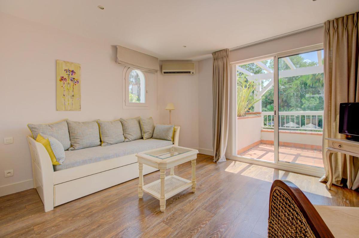 un salon avec un canapé et une porte coulissante en verre dans l'établissement Le Cottage - Hotel & Spa, à Argelès-sur-Mer