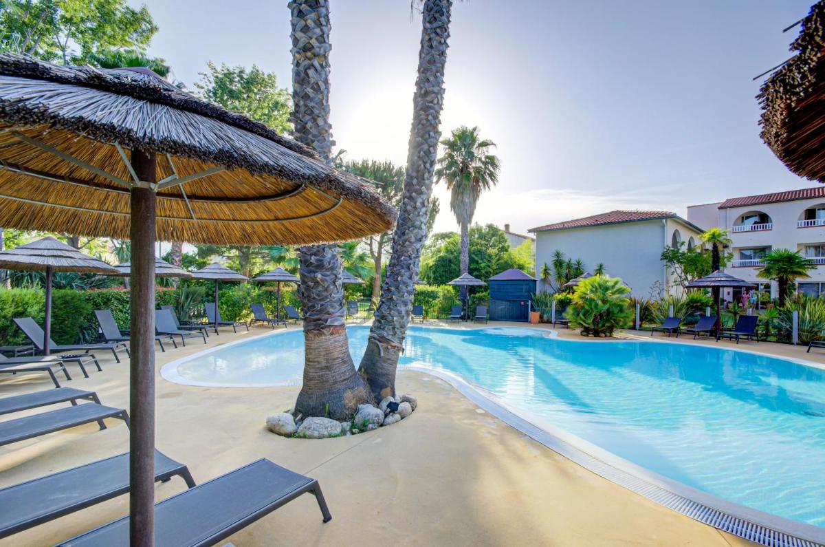 une piscine avec des palmiers, des chaises et un parasol dans l'établissement Le Cottage - Hotel & Spa, à Argelès-sur-Mer