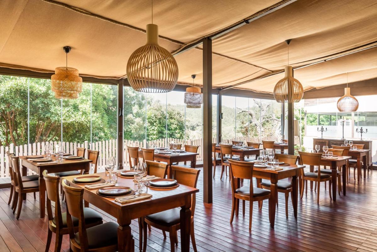 Un restaurante con mesas y sillas de madera y lámparas de araña. en Sant Pere del Bosc Hotel & Spa - Adults Recommended, en Lloret de Mar