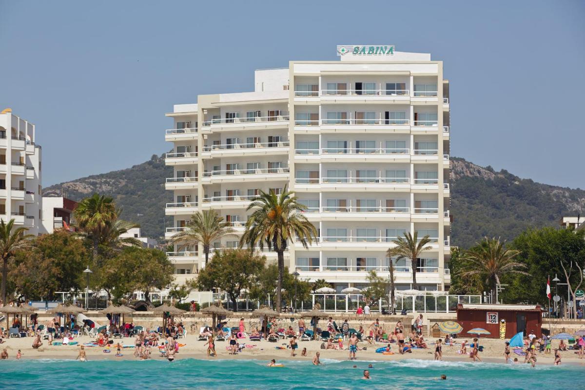 Un grupo de personas en una playa frente a un hotel. en Hotel Sabina, en Cala Millor