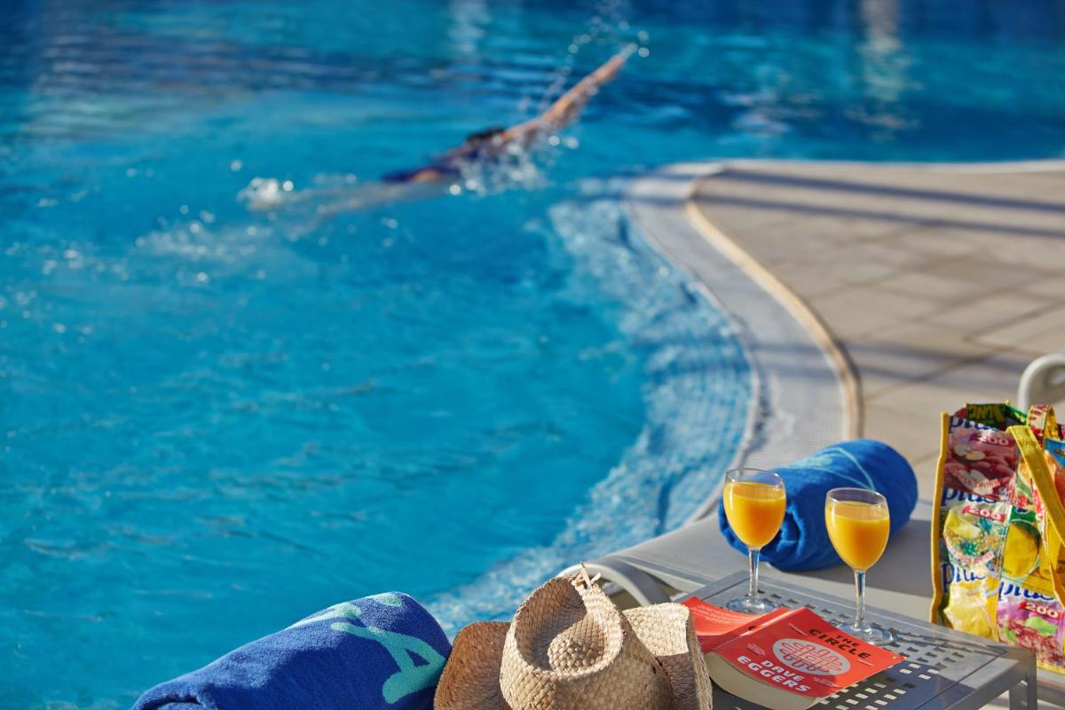 una persona nadando en una piscina con dos copas de vino en Hotel Sabina, en Cala Millor