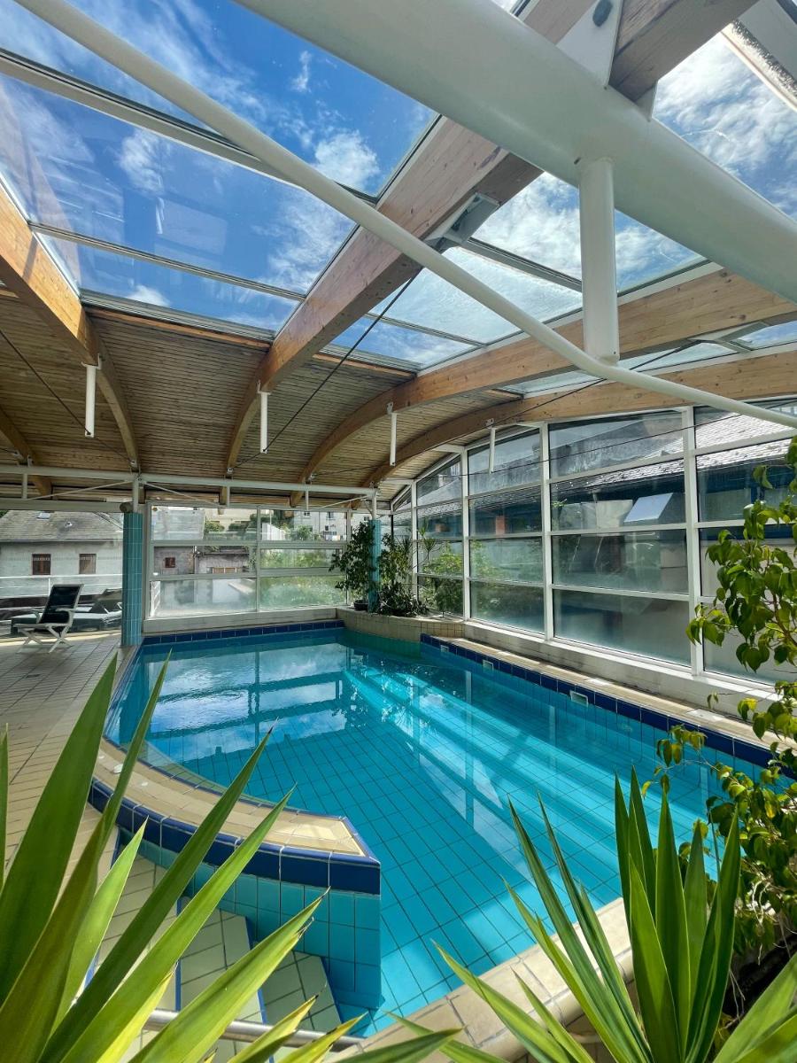 une piscine intérieure avec un plafond en verre dans l'établissement Logis Hôtel Regina, à La Bourboule