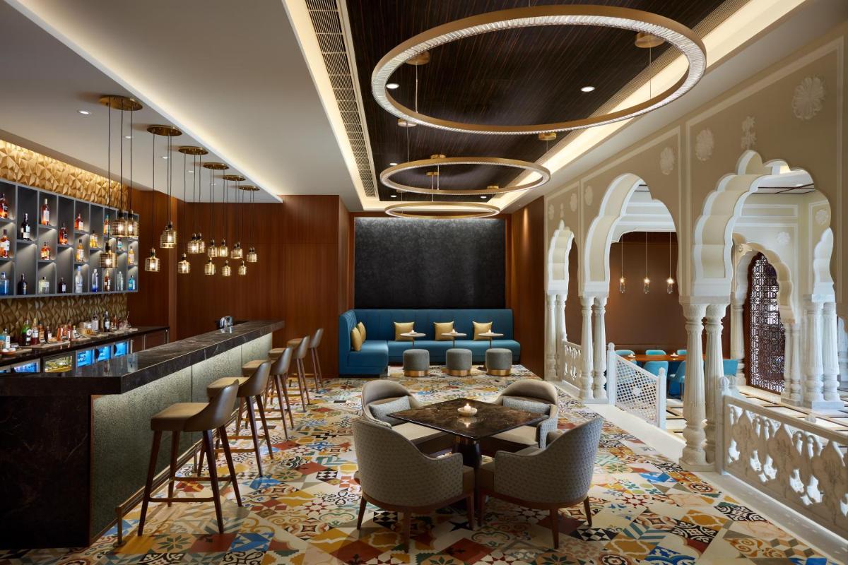 a hotel lobby with a bar and chairs at Hyatt Regency Jaipur Mansarovar in Jaipur a hotel lobby with a bar and chairs at Hyatt Regency Jaipur Mansarovar in Jaipur