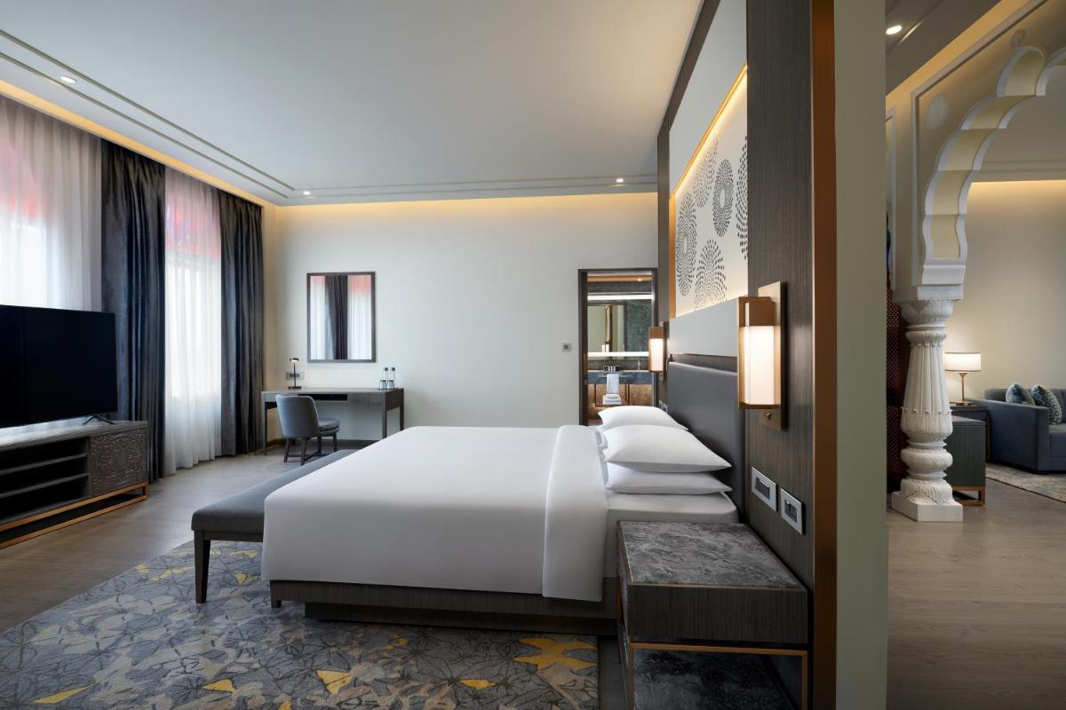 a bedroom with a white bed and a living room at Hyatt Regency Jaipur Mansarovar in Jaipur a bedroom with a white bed and a living room at Hyatt Regency Jaipur Mansarovar in Jaipur
