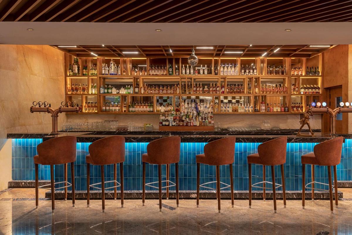 a bar with brown stools in a room at Radisson Blu Kaushambi Delhi NCR in Ghaziabad