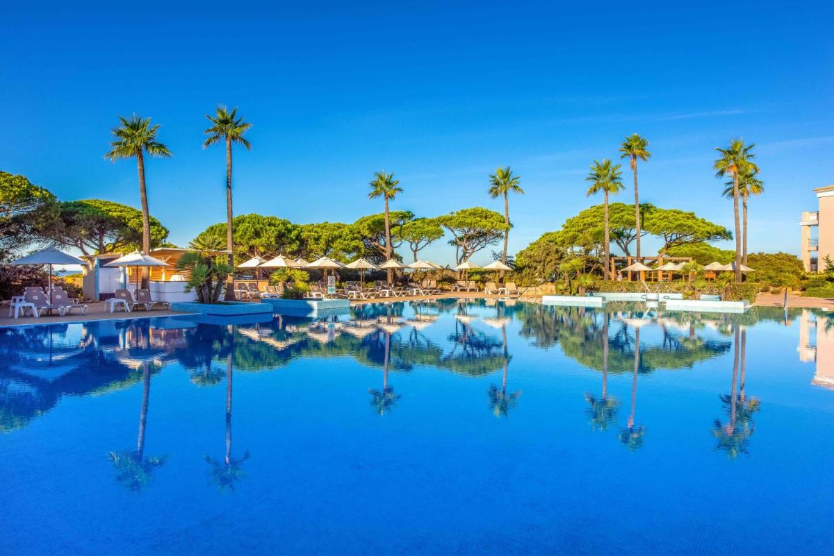 una piscina en un resort con palmeras en Valentin Sancti Petri, en Chiclana de la Frontera