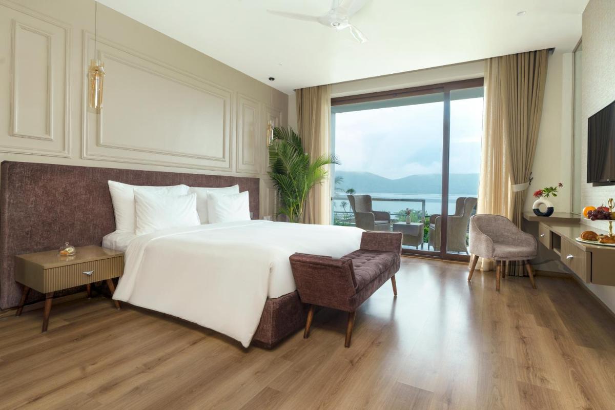 a bedroom with a large white bed and a large window at ZANA Lakeview Resort - most scenic lakeside resort in Udaipur