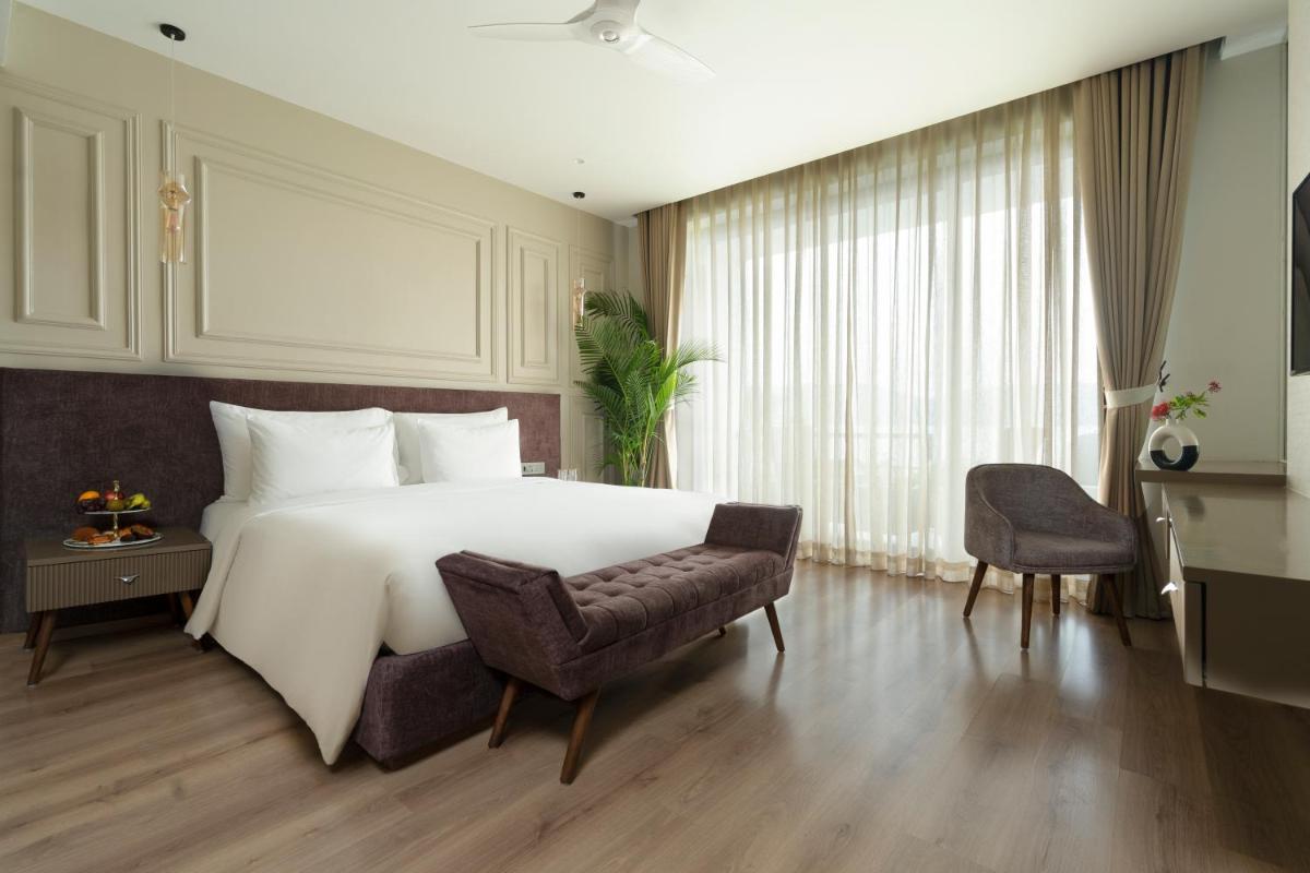 a bedroom with a large white bed and a chair at ZANA Lakeview Resort - most scenic lakeside resort in Udaipur