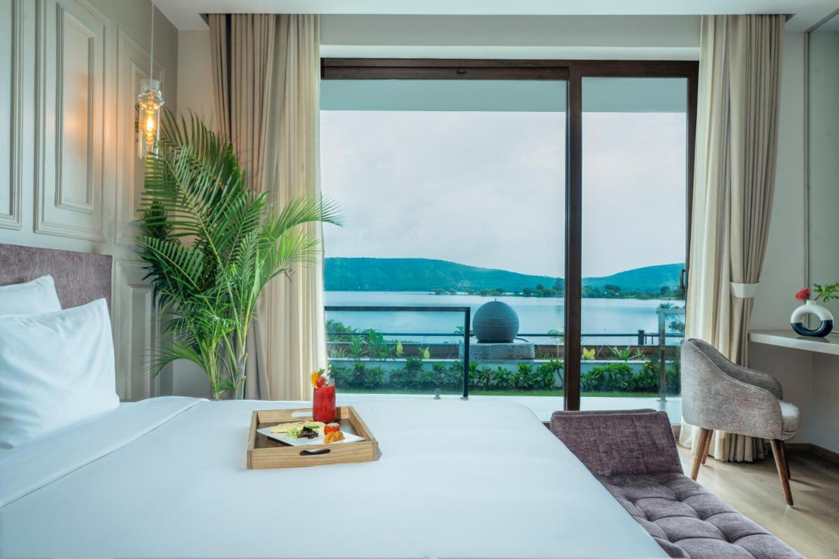 a bedroom with a large bed and a large window at ZANA Lakeview Resort - most scenic lakeside resort in Udaipur