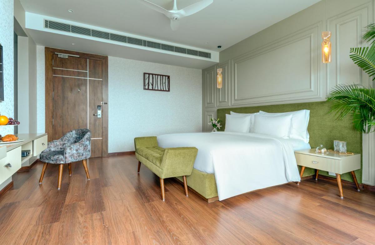a bedroom with a large white bed and a table and chairs at ZANA Lakeview Resort - most scenic lakeside resort in Udaipur