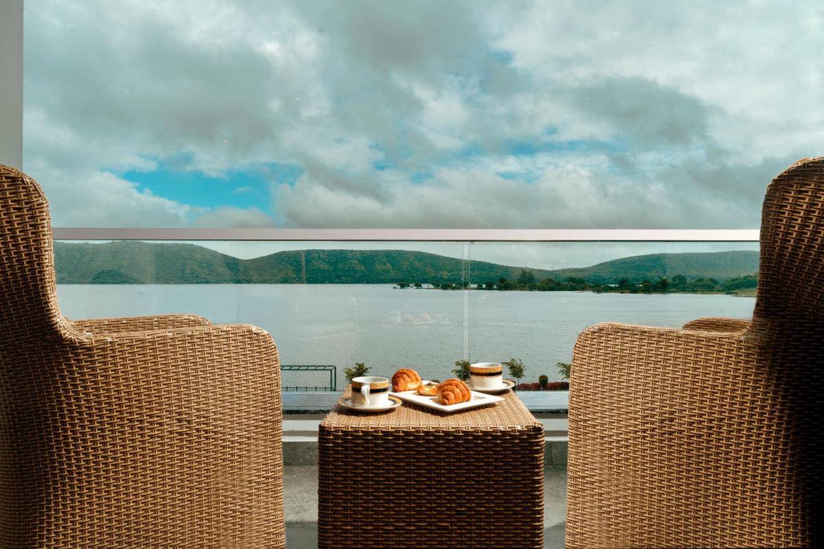 two chairs and a table with a plate of food at ZANA Lakeview Resort - most scenic lakeside resort in Udaipur