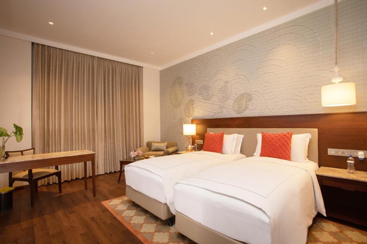 a hotel room with two beds and a desk at Taj Mahal Lucknow in Lucknow