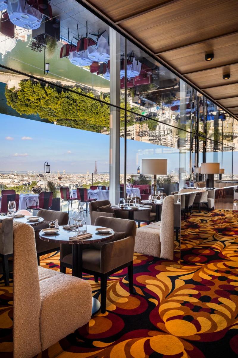 un restaurant avec des tables et des chaises et une grande fenêtre dans l'établissement SO/ Paris Hotel, à Paris