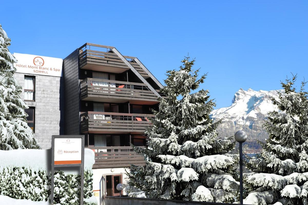 un hôtel avec des arbres enneigés devant lui dans l'établissement SOWELL HOTELS Mont Blanc et SPA, à Saint-Gervais-les-Bains