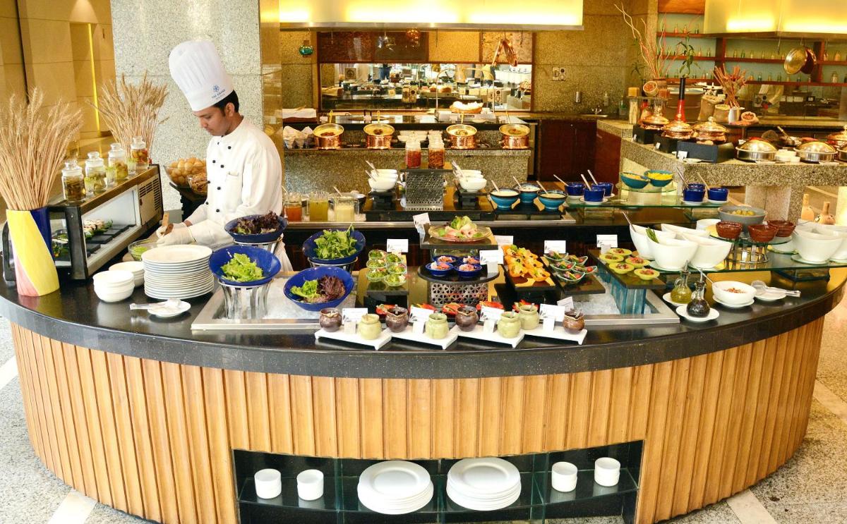 a chef standing behind a counter with food on it at The Grand New Delhi in New Delhi a chef standing behind a counter with food on it at The Grand New Delhi in New Delhi