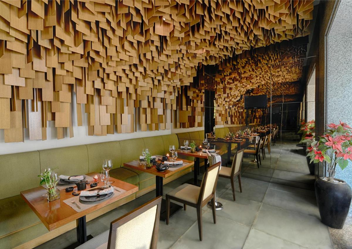 a restaurant with wooden walls and tables and chairs at The Grand New Delhi in New Delhi a restaurant with wooden walls and tables and chairs at The Grand New Delhi in New Delhi