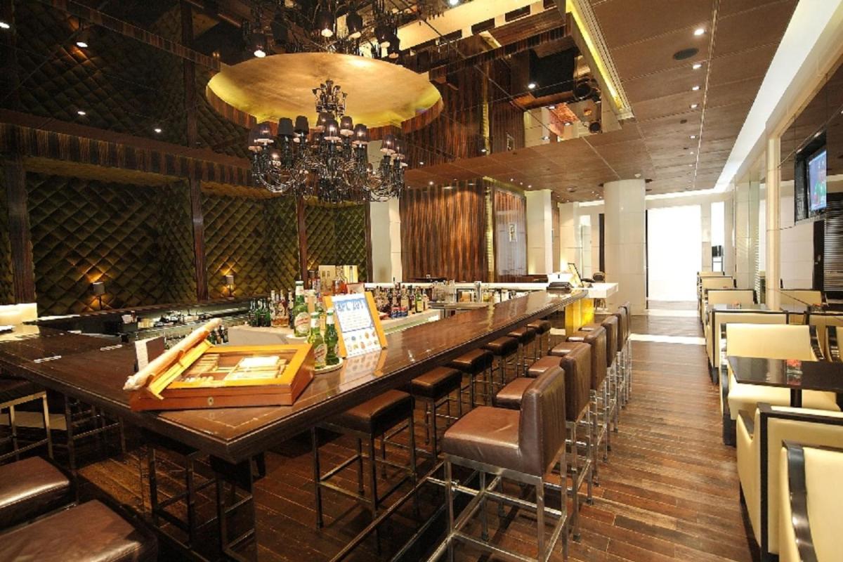 a restaurant with a long bar with leather chairs at The Grand New Delhi in New Delhi a restaurant with a long bar with leather chairs at The Grand New Delhi in New Delhi
