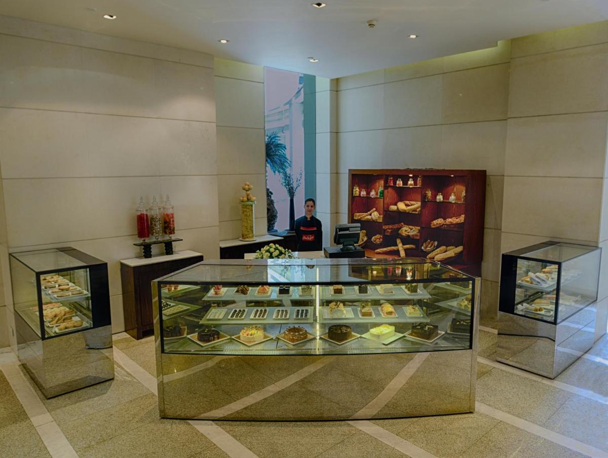 a man standing behind a display case in a bakery at The Grand New Delhi in New Delhi a man standing behind a display case in a bakery at The Grand New Delhi in New Delhi