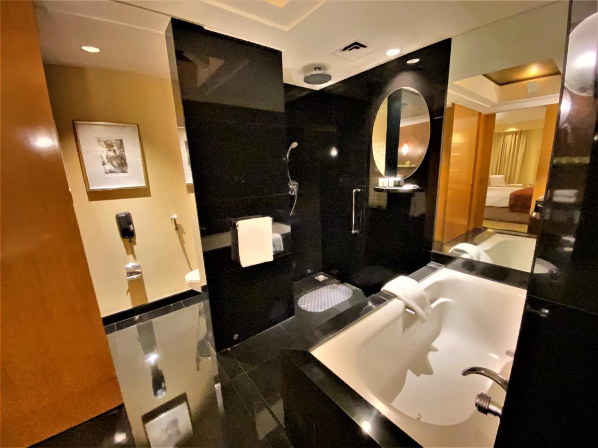 a bathroom with a tub and a sink and a mirror at The Grand New Delhi in New Delhi a bathroom with a tub and a sink and a mirror at The Grand New Delhi in New Delhi