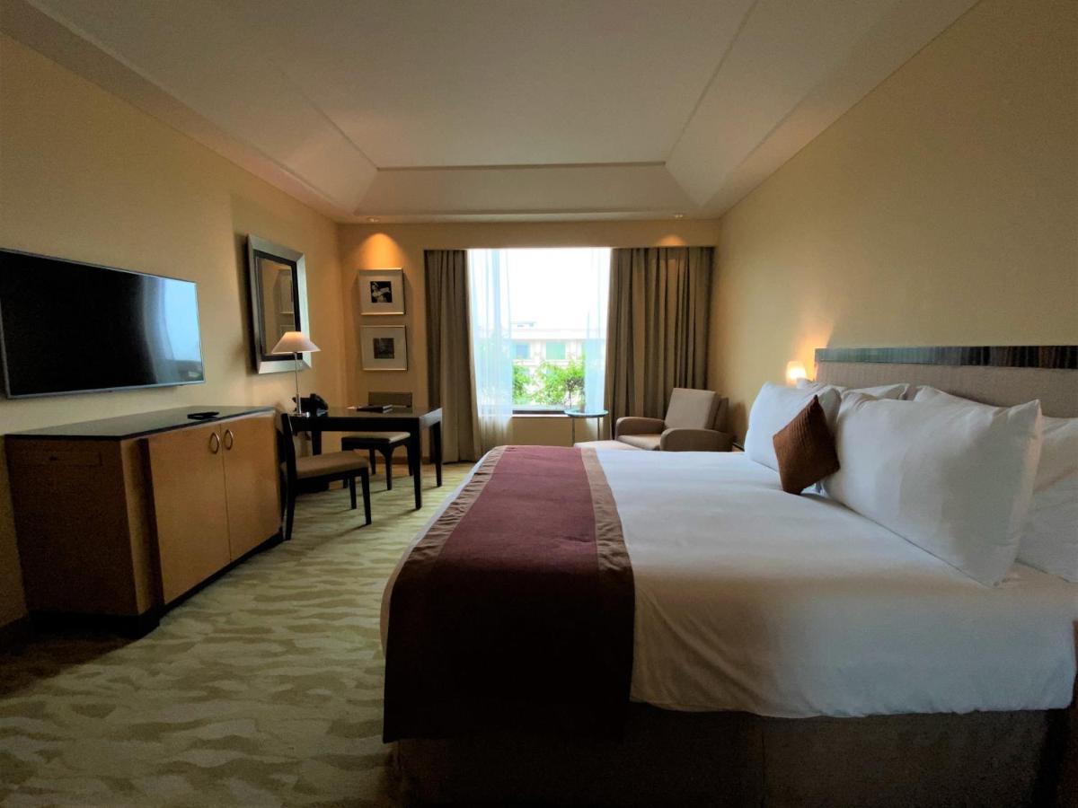 a hotel room with a large bed and a television at The Grand New Delhi in New Delhi a hotel room with a large bed and a television at The Grand New Delhi in New Delhi