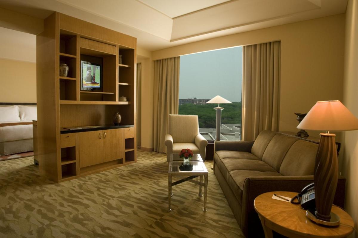 a living room with a couch and a large window at The Grand New Delhi in New Delhi a living room with a couch and a large window at The Grand New Delhi in New Delhi