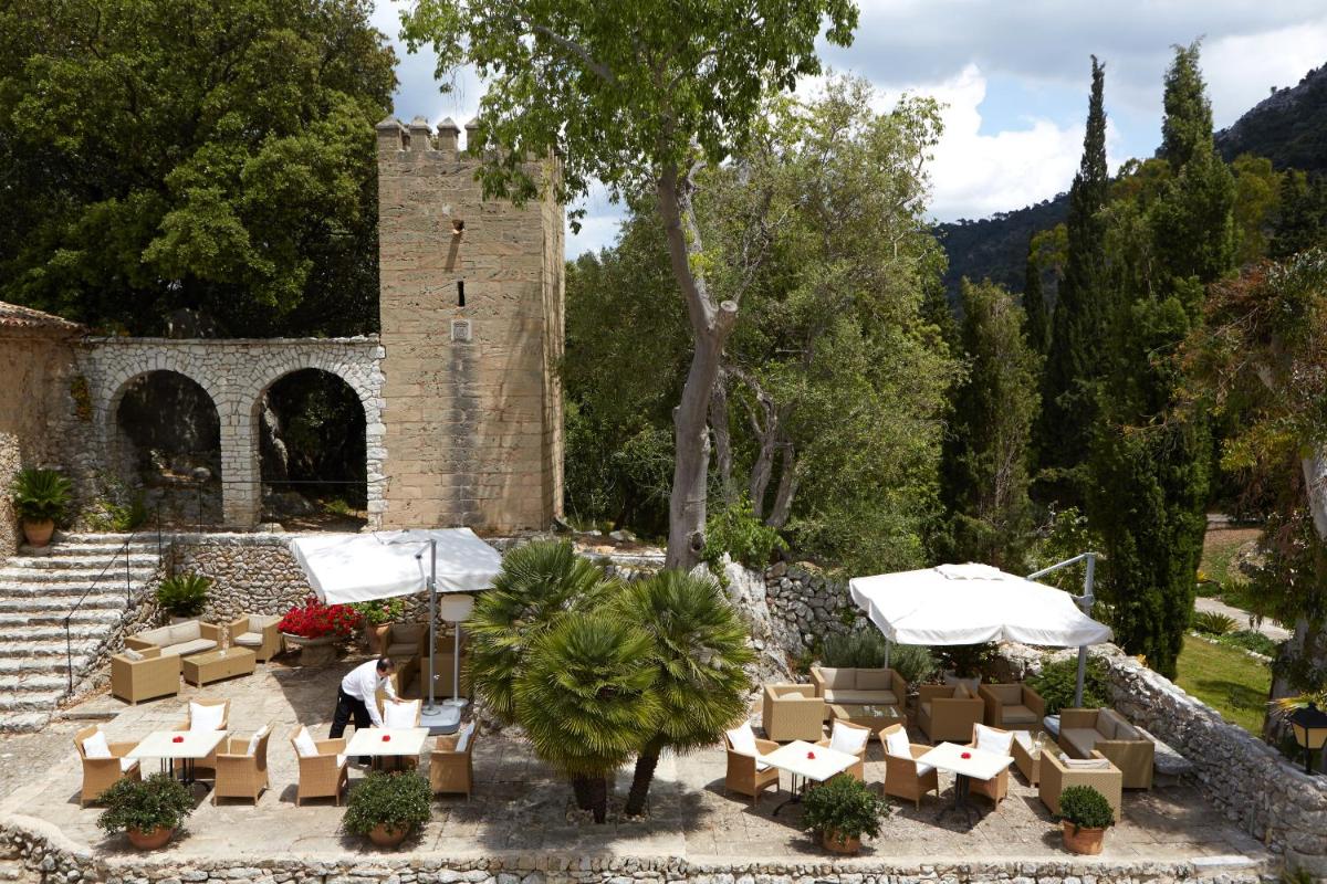 Un patio con mesas y sillas frente a un edificio. en L’Hermitage Hotel & Spa, en Orient
