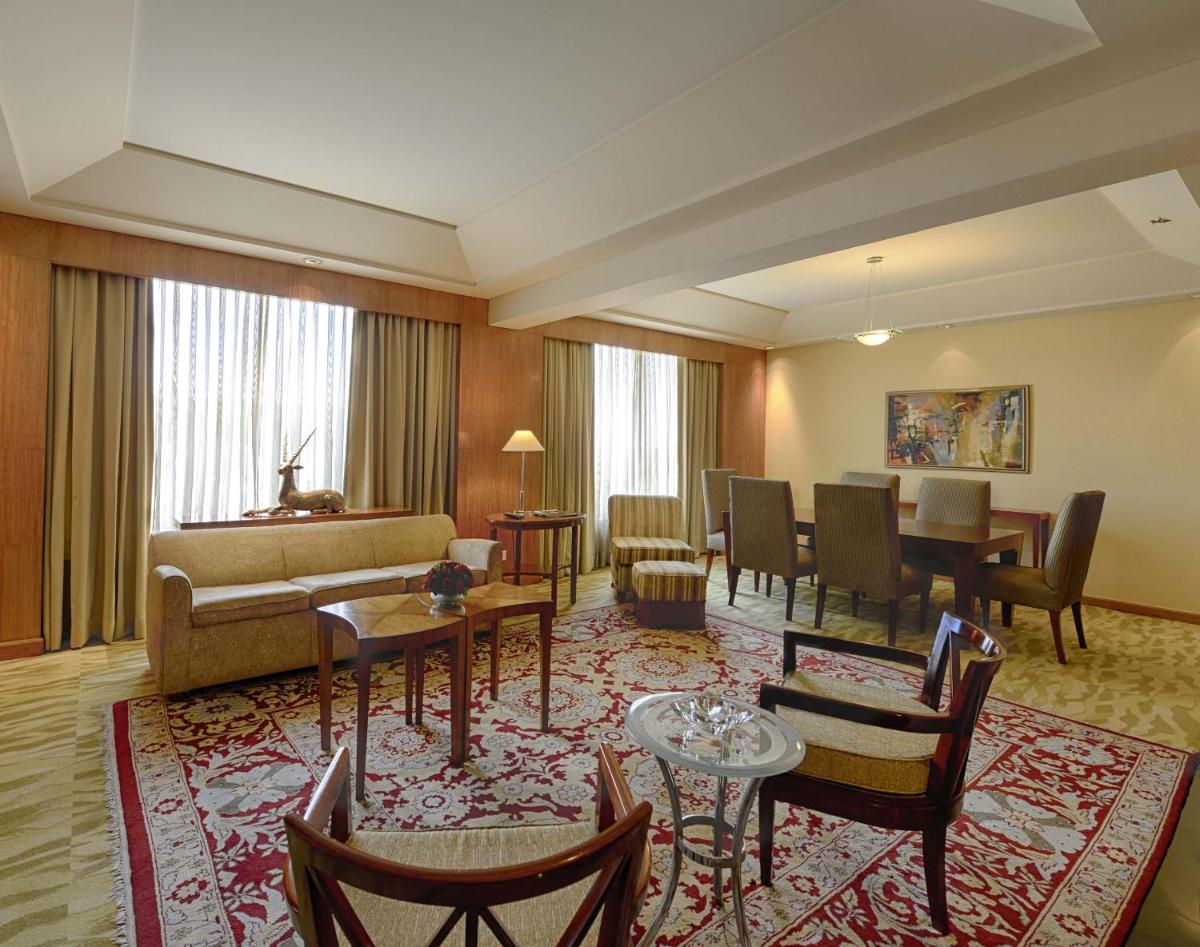 a living room with a couch and tables and chairs at The Grand New Delhi in New Delhi a living room with a couch and tables and chairs at The Grand New Delhi in New Delhi