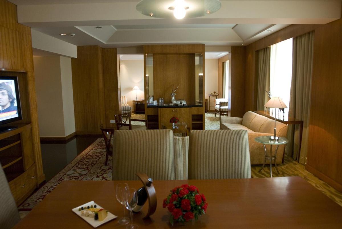 a room with a table and chairs and a living room at The Grand New Delhi in New Delhi a room with a table and chairs and a living room at The Grand New Delhi in New Delhi