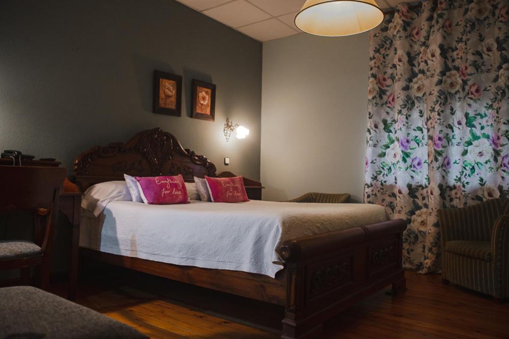 Un dormitorio con una cama grande con almohadas rosas. en Balneario de Corconte, en Cabañas de Virtus