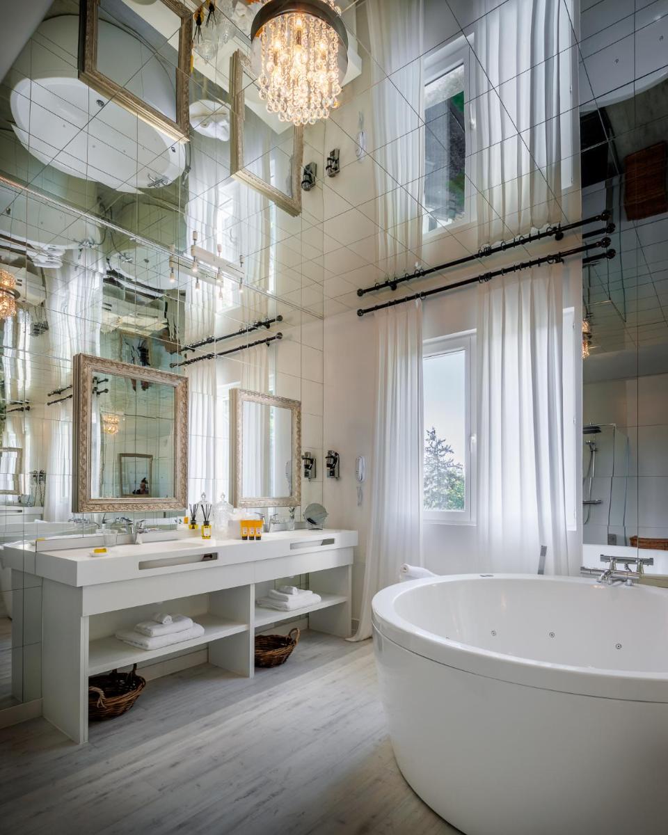La salle de bains est pourvue d'une baignoire, de 2 lavabos et d'un grand miroir. dans l'établissement Belfry & Spa by Ligne St Barth, à Lourdes