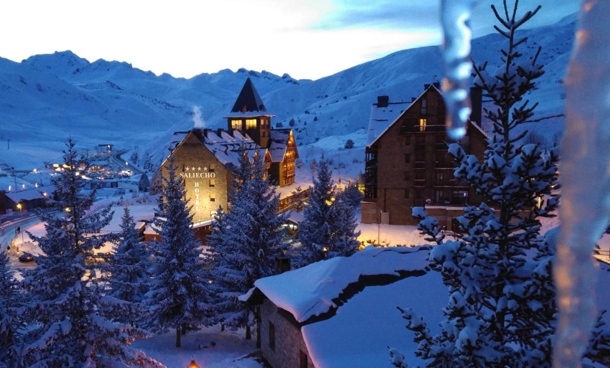 una ciudad cubierta de nieve por la noche con un edificio en Hotel Saliecho, en Formigal
