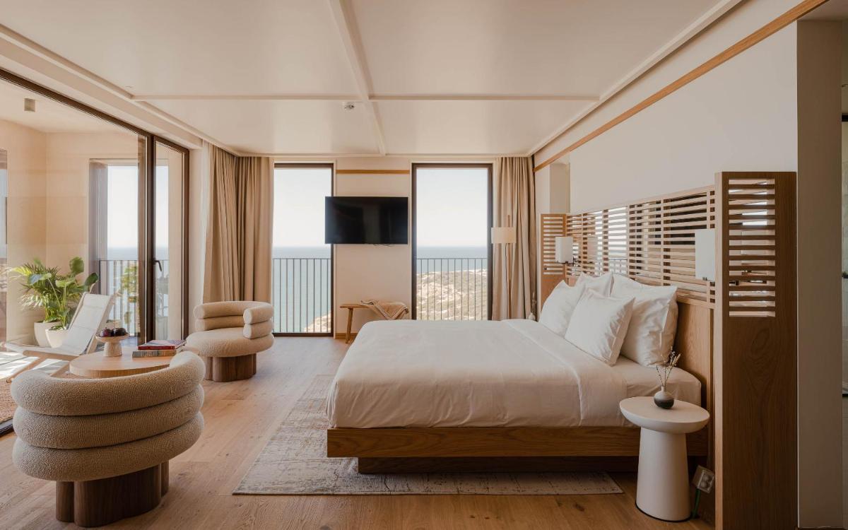 um quarto com uma cama grande e uma varanda em Aethos Ericeira na Ericeira