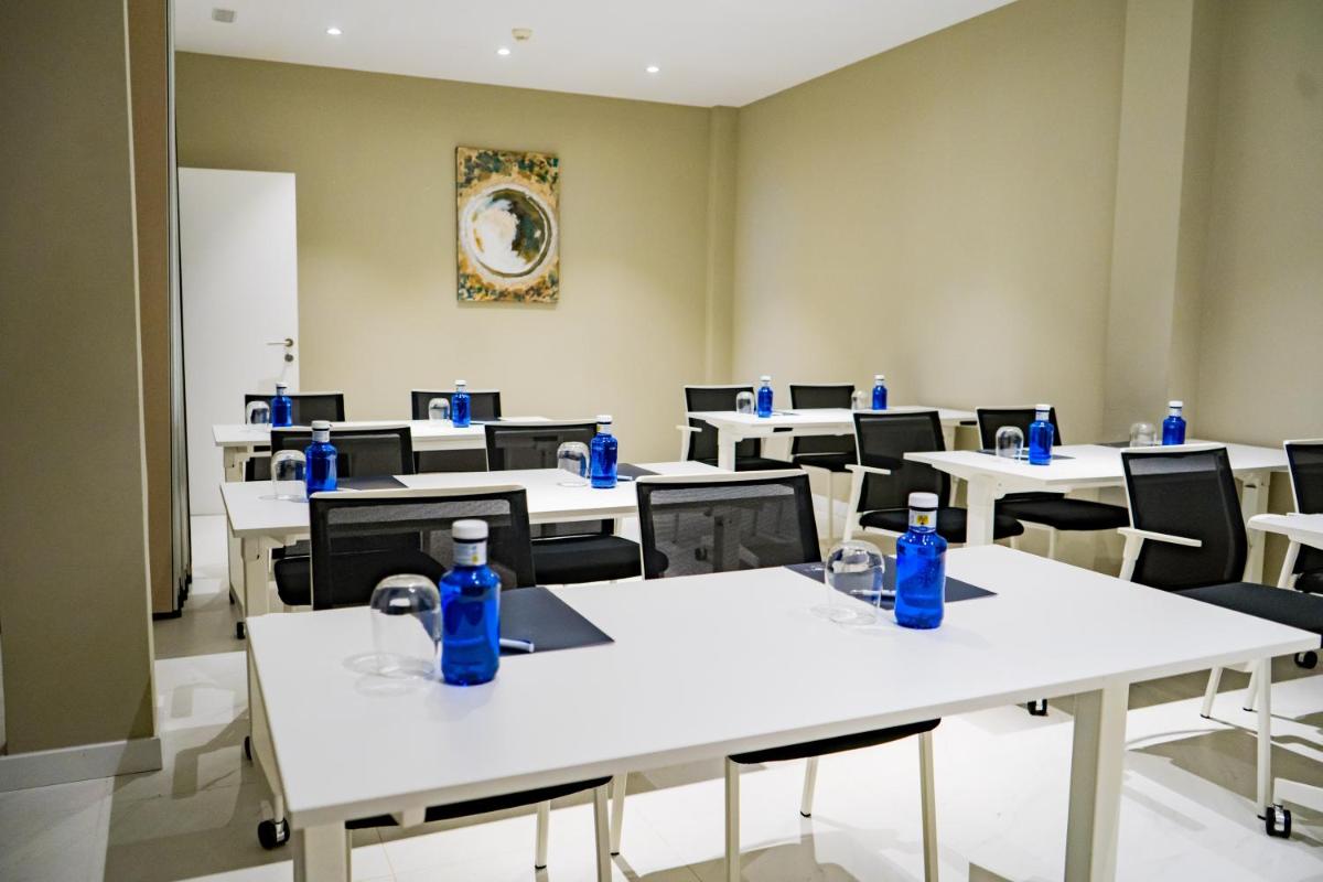 Un aula con mesas blancas y botellas azules sobre ellas. en Moon Hotel & SPA., en Aguadulce 129 fotos más